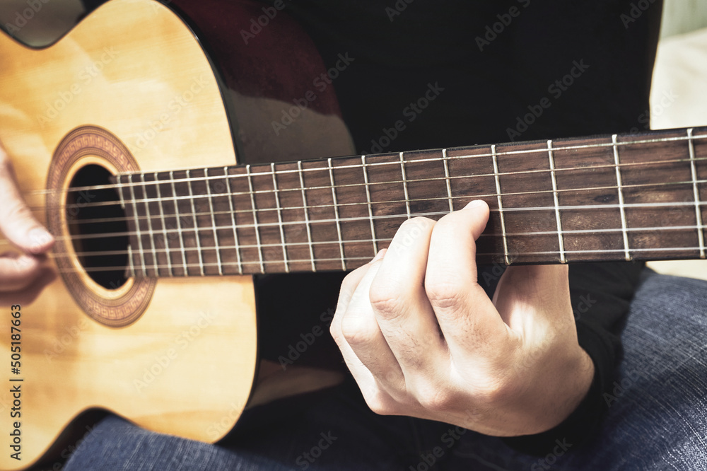 Close-up of a male hand on the fretboard of a classical guitar
