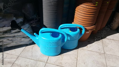 Blue plastic gardening watering containers and pots are displayed together, reflecting everyday gardening tools used for plant care, irrigation, and simple outdoor or indoor gardening routines.