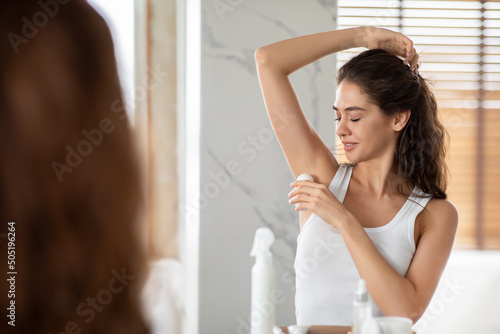 Lady Applying Antiperspirant On Armpit For Freshness In Modern Bathroom