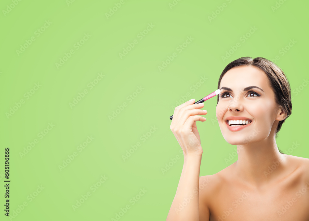 Portrait of beautiful dark haired woman with makeup cosmetics brush, isolated over green background. Happy smiling brunette girl looking up, at studio. Beauty model image. Portrait of beautiful dark haired woman with makeup cosmetics brush, isolated over green background. Happy smiling brunette girl looking up, at studio. Beauty model image.