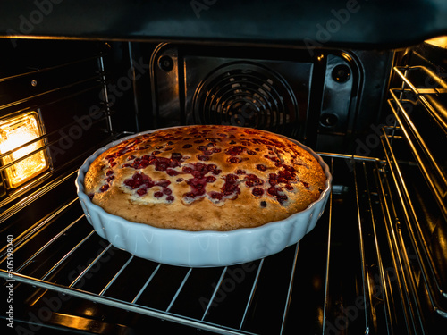 Cooking a sponge cake with berries in the oven.