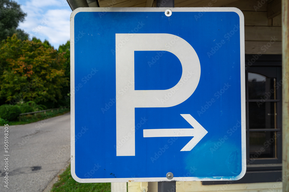 Blue square sign with p letter and a right arrow at a parking lot for cars Blue square sign with p letter and a right arrow at a parking lot for cars