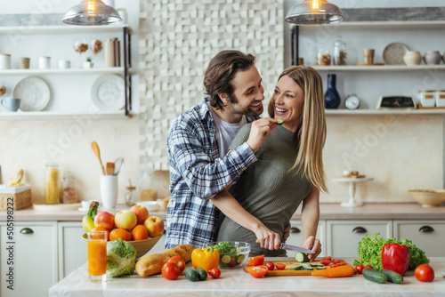 Foto Happy caucasian millennial husband with stubble feeds blonde wife, couple have f