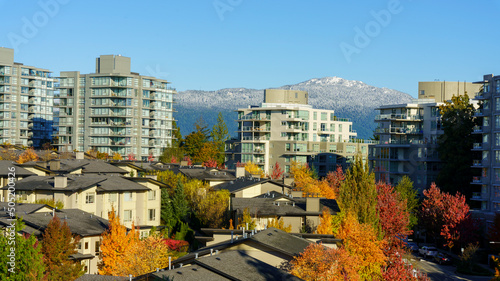 Aerial Fall view of BC residential community with snow-covered alpine mountain backdrop.
