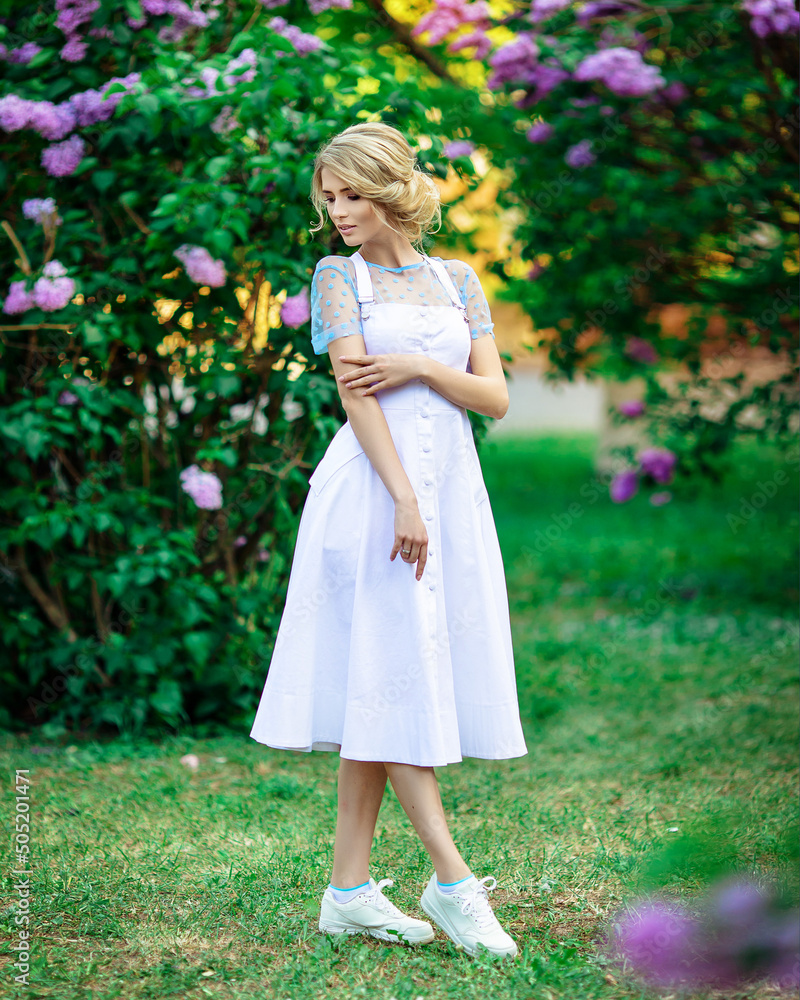beautiful blonde in a white dress outdoors among lilacs beautiful blonde in a white dress outdoors among lilacs