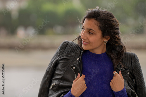 latin young woman with jacket getting wet in the rain