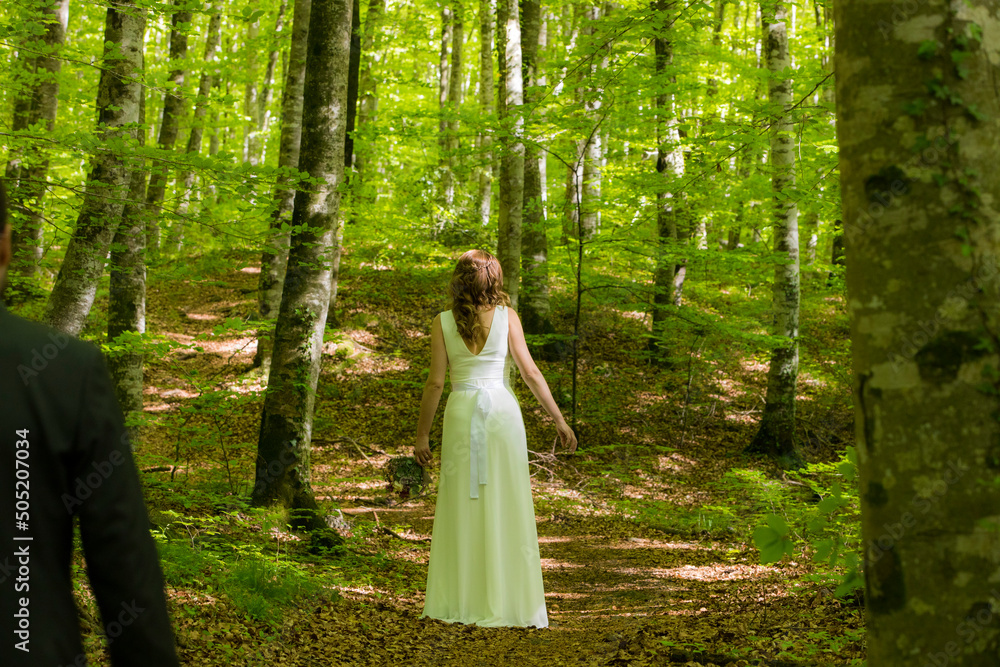 Bride in white dress walking through the spring forest in La Fageda d en Jorda, La Garrotxa, Spain Bride in white dress walking through the spring forest in La Fageda d en Jorda, La Garrotxa, Spain