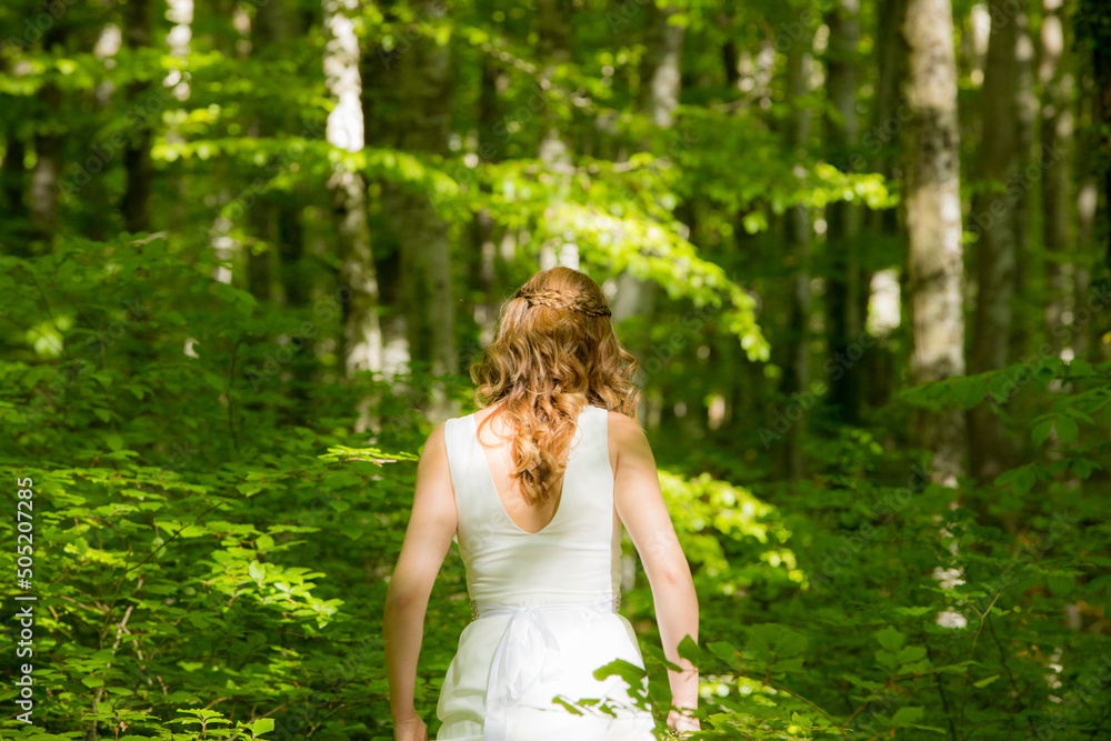Bride in white dress walking through the spring forest in La Fageda d en Jorda, La Garrotxa, Spain Bride in white dress walking through the spring forest in La Fageda d en Jorda, La Garrotxa, Spain