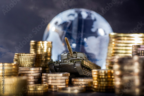 Stacks of money and a tank in front of a globe symbolizing global armament and finance photo