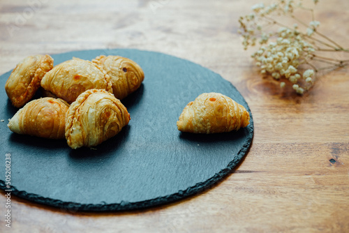 Curry puff pastry in a stone plate placed on a wooden table.