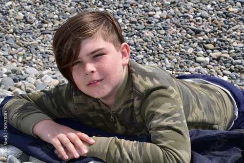 Boy lying on a pebble beach close-up