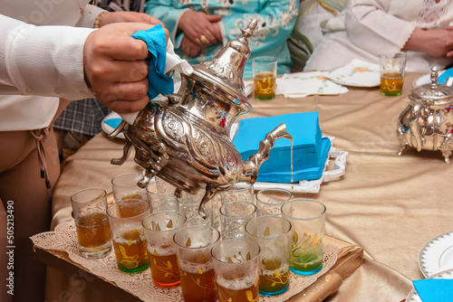 A Moroccan man pours tea into cups. Moroccan mint tea