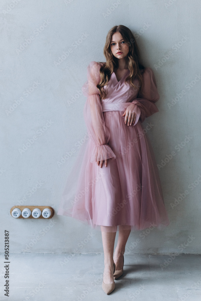 Elegant young girl in fashion dress on grey isolated background. Pretty curly fashion woman portrait Elegant young girl in fashion dress on grey isolated background. Pretty curly fashion woman portrait