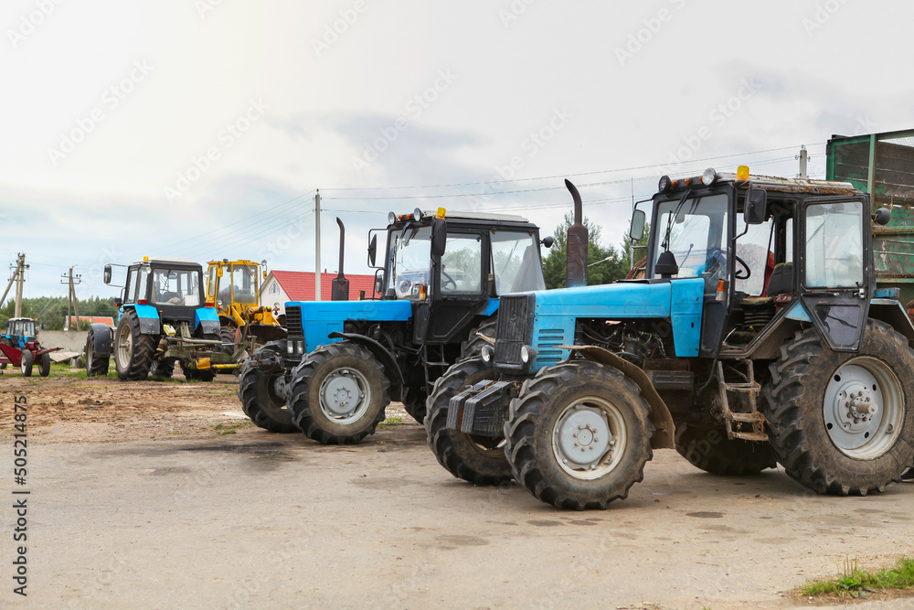 Agricultural machinery, tractors and equipment outdoors, near the garage, ready to work in the field.