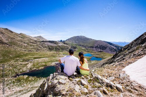 Young couple hikers standing on top of the mountain and enjoying valley view in La Cerdanya, Pyrenees, Spain