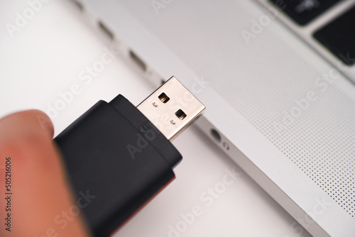 Vászonkép A USB Flash Drive in person hand and laptop near