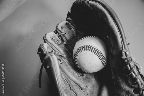 Black and white photo of a baseball resting in a Baseball glove 