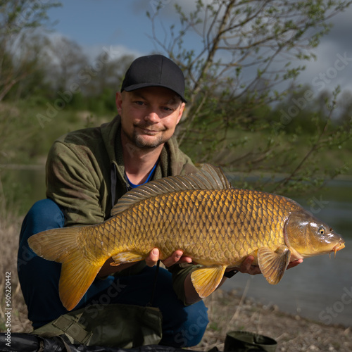 Angler holding a big Common Carp. Freshwater fishing and trophy fish. 