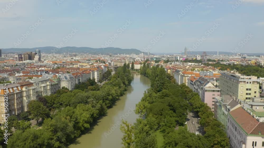 Aerial backward moving shot of Danube river flowing surrounded by residential buildings in Vienna, Austria is one of the most famous capital cities of Europe at daytime. Aerial backward moving shot of Danube river flowing surrounded by residential buildings in Vienna, Austria is one of the most famous capital cities of Europe at daytime.