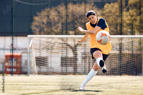 Female soccer player kicking the ball while having sports training on stadium.
