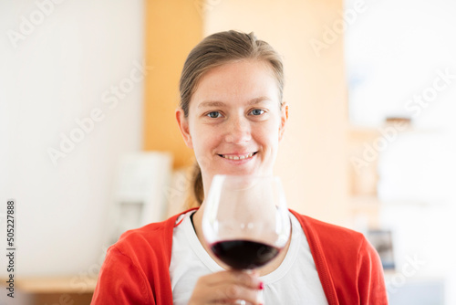 Junge blonde Frau zu Hause entspannt mit einem Glas Rotwein au fem Sofa