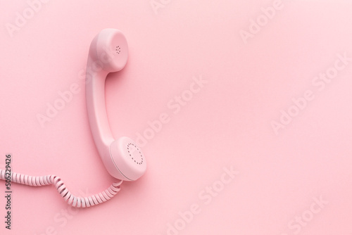 Pink telephone receiver on pink background photo