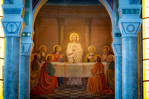Fresco representing Jesus holding the host in his hands surrounded by the apostols during the last supper. Inside of a catholic church