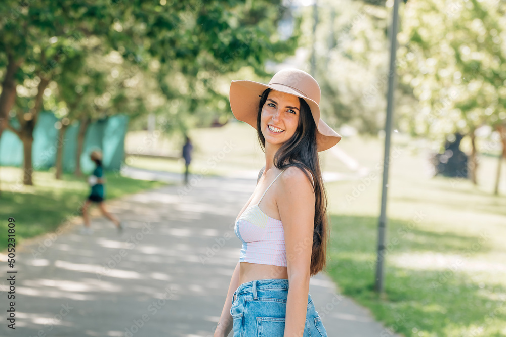 happy girl in hat walking on the street in summer