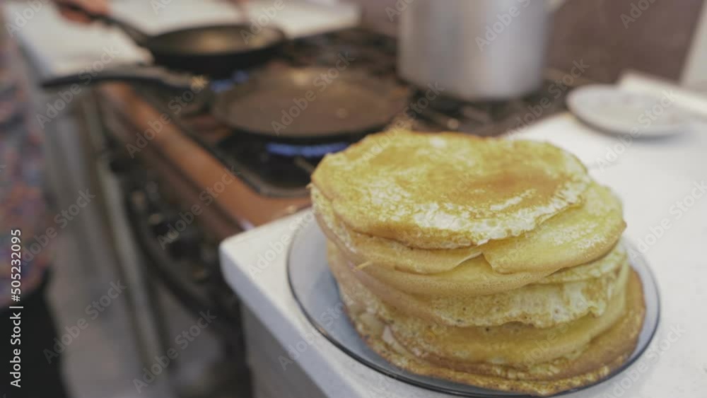 housewife bakes pancakes on two frying pans for a large family housewife bakes pancakes on two frying pans for a large family