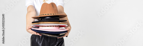 Fotografija Fashionable woman with many hats, posing on gray background