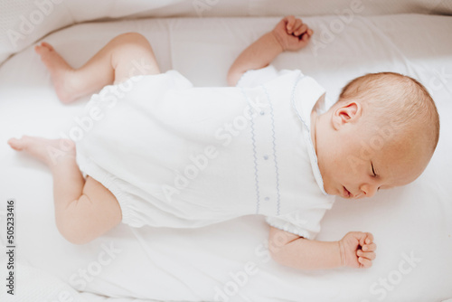 Close up newborn baby boy sleeping in the crib. Horizontal photo.