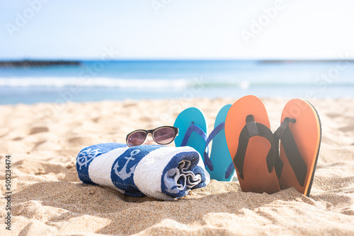 Beach shoes, towel and sunglasses on the sand on a beach
