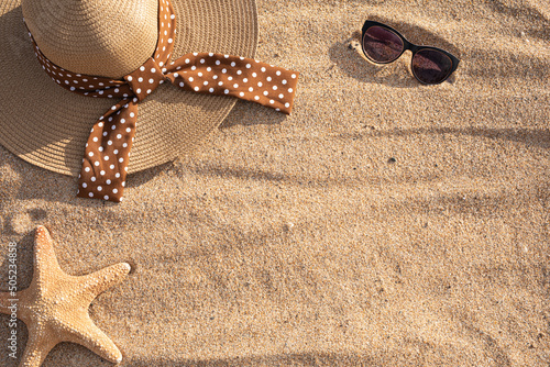 Hat, sunglasses and starfish in the sand of a beach with copy space