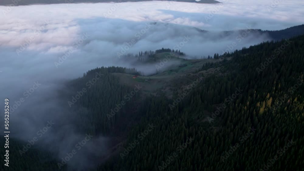 Flying towards sea of clouds floating over mountain valley. Long sunrise shadows falling on fog Flying towards sea of clouds floating over mountain valley. Long sunrise shadows falling on fog