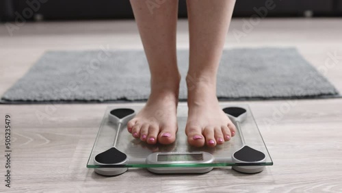 Girl Legs Step On Bathroom Scale. Woman On Scales Measure Weight. Human Barefoot Measuring Body Fat Overweight. Slim Woman Checking BMI Weight Loss. Diet Female Feet Standing Weighing Scales On Room. photo