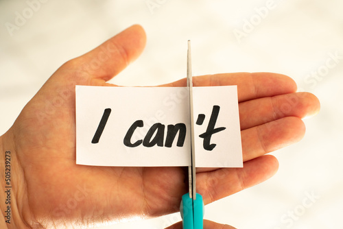 Woman hand cut letter t from I can't written text. 
Self Motivational photo.