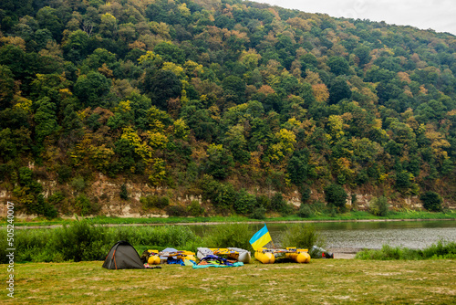 a tourist tent and three catamarans under Ukrainian flag on Dnister riverside, National Nature Park Dnister Canyon, Ukraine