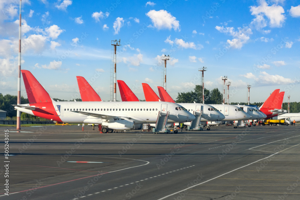 Fototapeta premium Many identical jet planes in the airport parking lot in a row