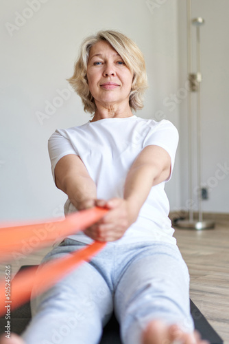 Home training concept. Strong senior woman doing exercises with dumbbells indoors. Cheerful mature lady working out her arm muscles, keeping fit, leading healthy lifestyle