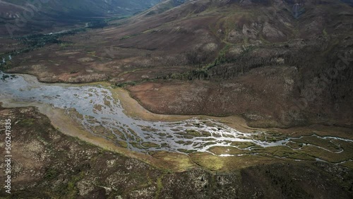 A river in mountain valleys with permafrost landforms, aerial reveal shot photo