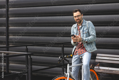 Guy sitting on a bicycle using his mobile phone.