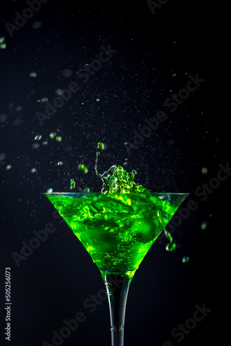 Green soft drink with splashing soda in a glass