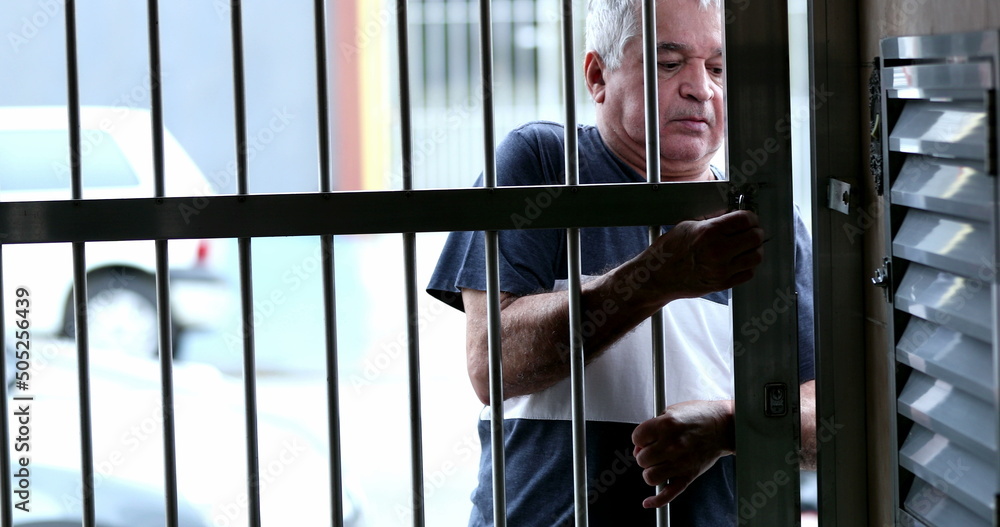 Older man sliding metal gate entrance and leaving house Older man sliding metal gate entrance and leaving house