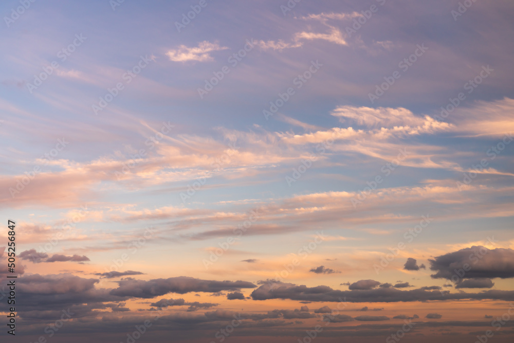 Beautiful sky replacement background with pink, yellow and orange colored clouds on a blue sky backdrop.
