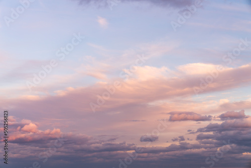 Beautiful sky replacement background with pink, yellow and orange colored clouds on a blue sky backdrop.