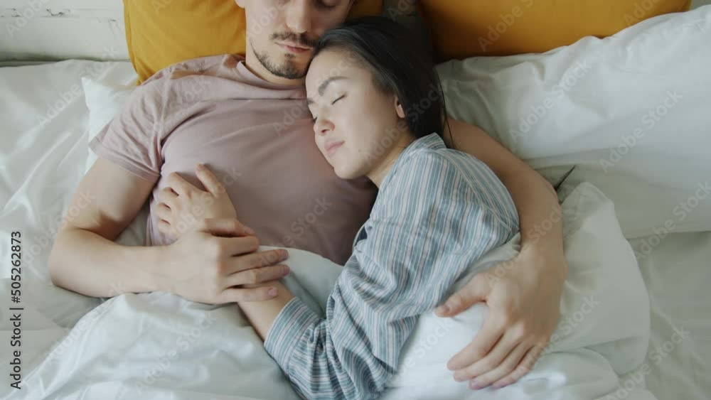 Top view of girlfriend and boyfriend sleeping in bed together embracing expressing love enjoying rest. Relationship and lifestyle concept. Top view of girlfriend and boyfriend sleeping in bed together embracing expressing love enjoying rest. Relationship and lifestyle concept.