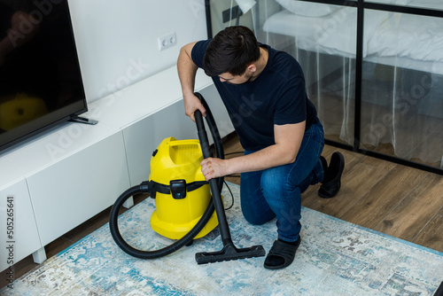 professional cleaner vacuuming carpet and floor with yellow vacuum cleaner
