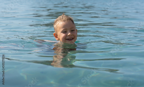 The child learns to swim. Happy child swims in the sea. Holidays in Greece photo