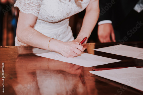 Una mujer vestida de blanco firma un papel. Concepto de firmar los papeles de la boda en una ceremonia civil. Novia renovando sus votos. photo
