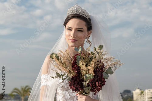 Uma jovem mulher usando um vestido de noiva com céu nublado ao fundo. photo